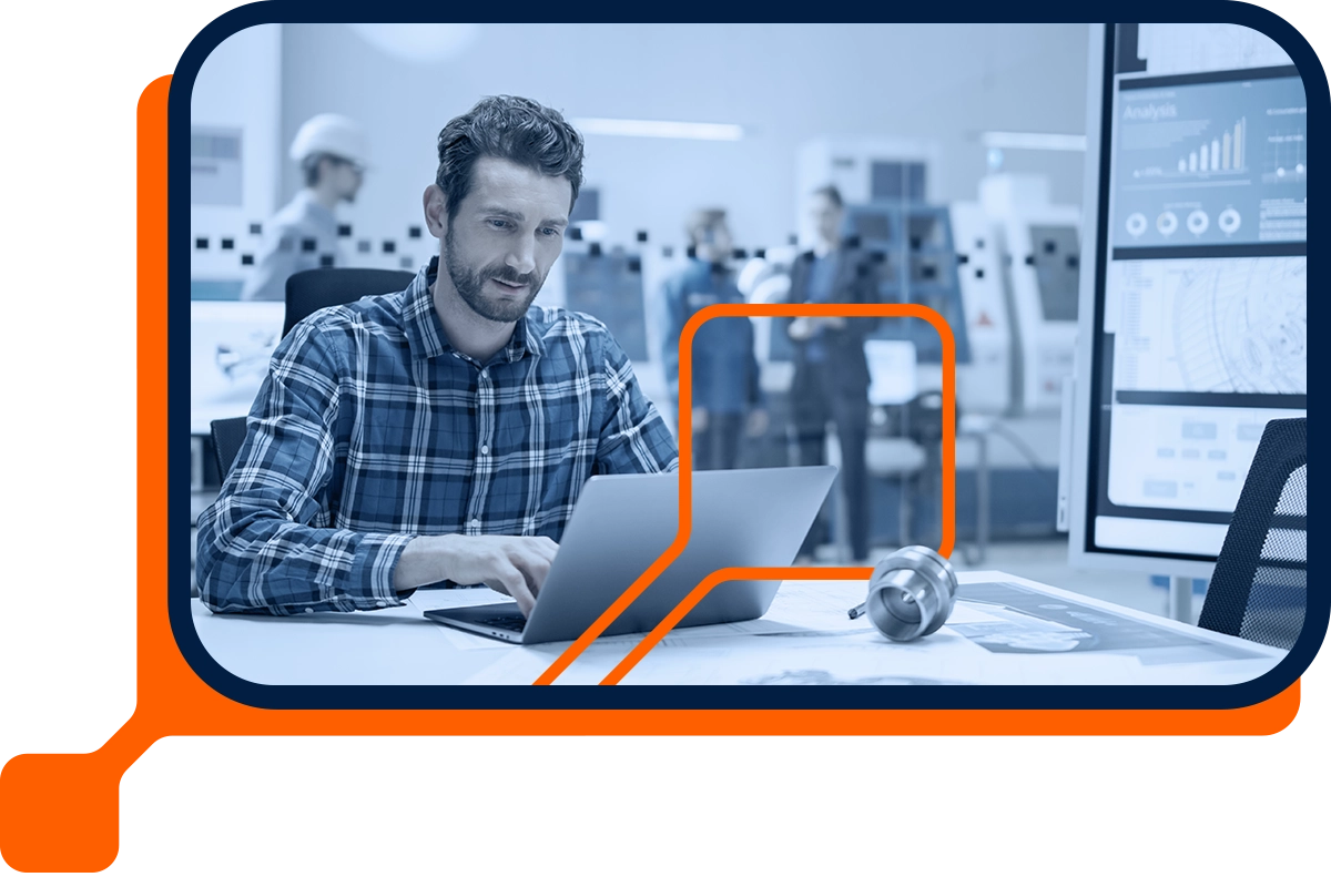 Industrial Engineer Sitting at His Desk, Working on Laptop Computer, Analyzing